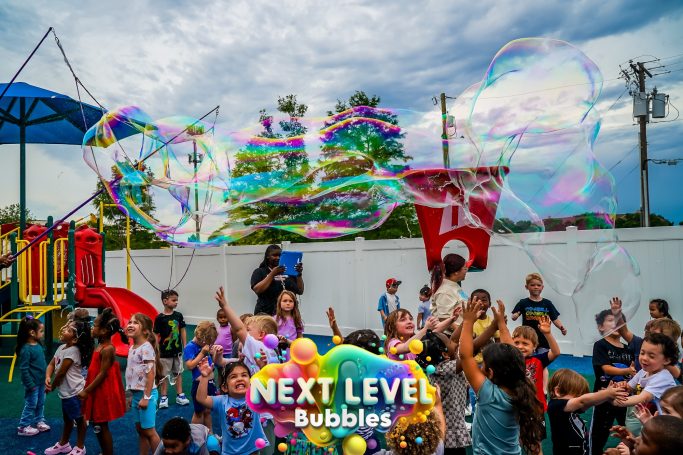 Children playing joyfully with bubbles at a colorful outdoor playground.