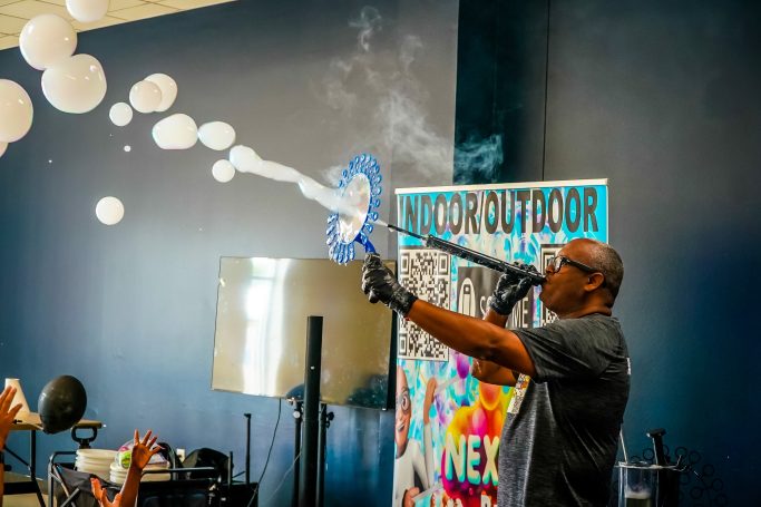 A performer creates large bubbles at a lively indoor event.